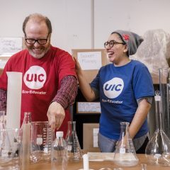 Two people wearing UIC t-shirts, standing in a lab