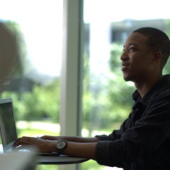 Person sitting at computer, smiling