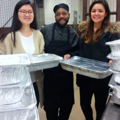 Three people holding trays of food waste to be composted
